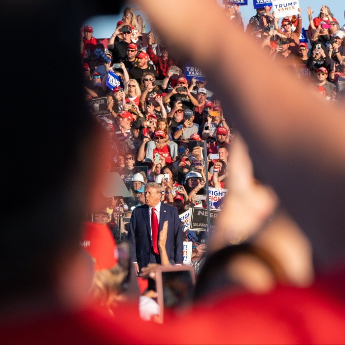 View between the heads of spectators of Donald Trump as he speaks at a rally