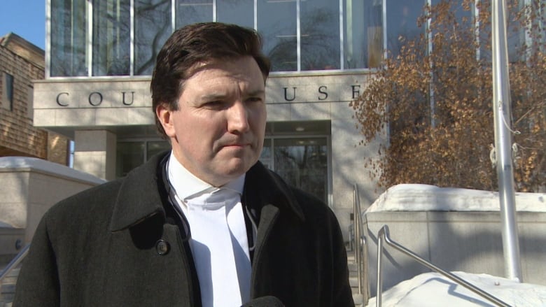 Man stands outside of snowy courthouse.