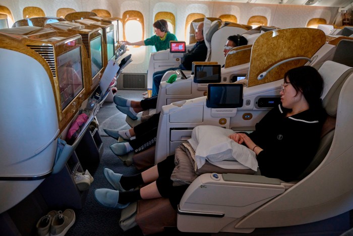 Emirates business class passengers sleeping or watching TV during a flight in February 2024