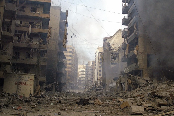 Badly damaged apartment blocks, with piles of rubble between the street between them