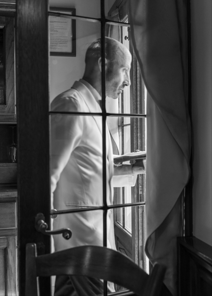 A black and white photograph of a waiter in profile at Villa 600, looking out of a window