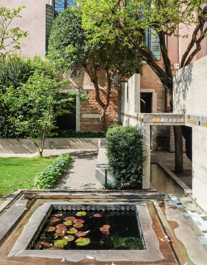 A pond and small lawn and architect Carlo Scarpa’s Modernist stone detailing in the garden of the Fondazione Querini Stampalia