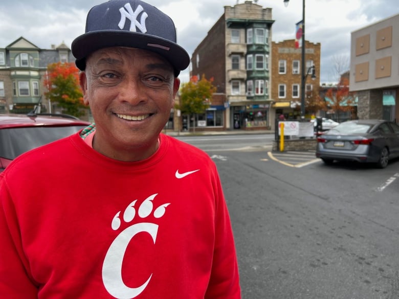 Man with Yankees cap in front of street with prewar architecture