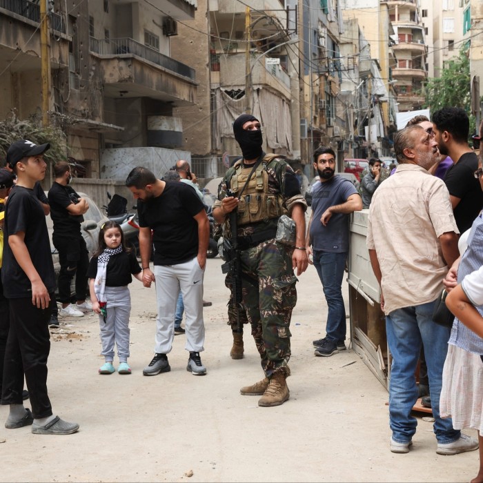 Lebanese military personnel and people gather at the site of an Israeli strike