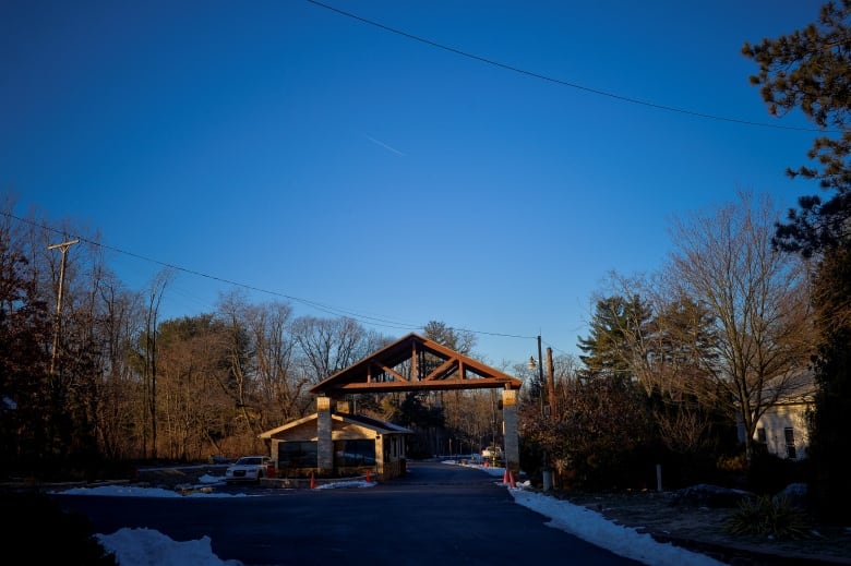 A long driveway and a gate in what appears to be a rural area is shown.