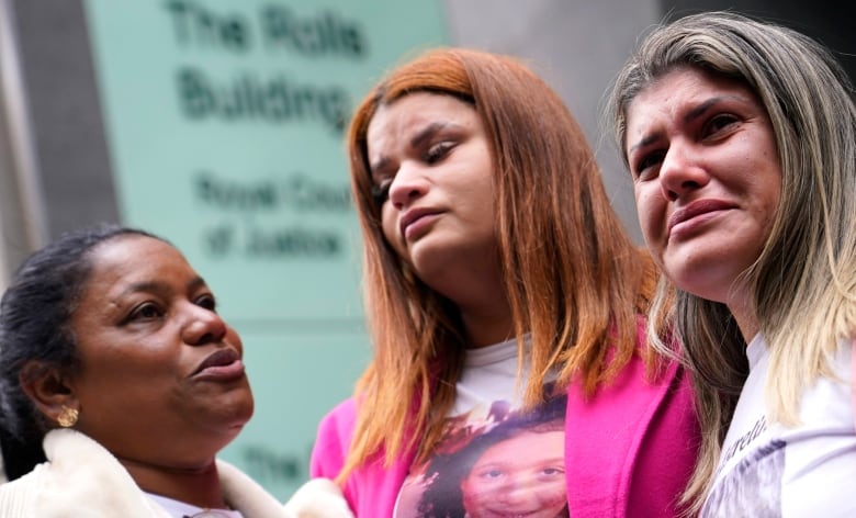 Three women are pictured from the shoulders up. The woman on the right side is tearing up, her face contorted with emotion. 