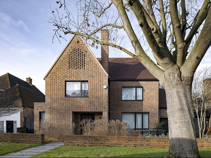 A modern two-story brick house with large square windows and a gabled roof, set behind a low brick wall