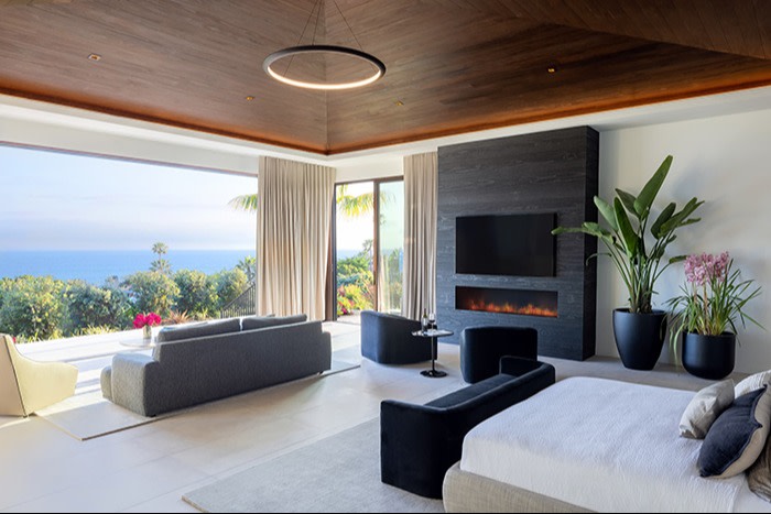 A modern, luxurious living room with an open layout that features a large panoramic window overlooking the ocean