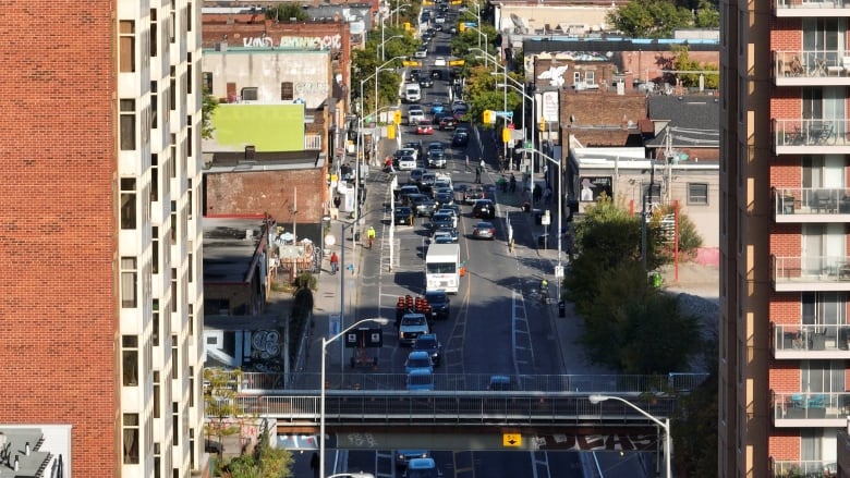 An aerial shot shows a road with cars and cyclists.