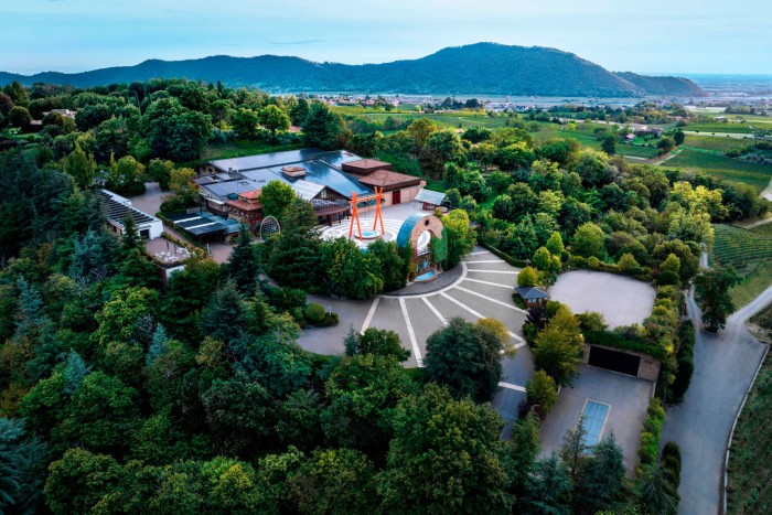 An aerial view of Bellavista winery’s central buildings, surrounded by woodland, with hills in the distance