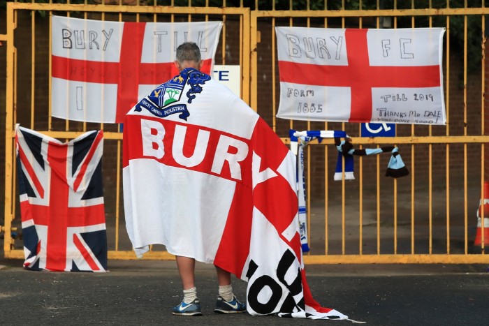 A Bury fan at the gates of Gigg Lane stadium