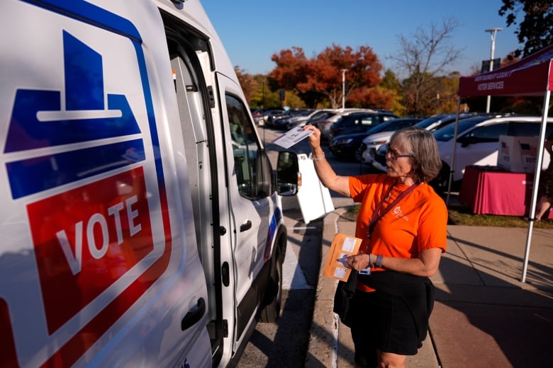 Woman drops off ballot in van that says "VOTE"