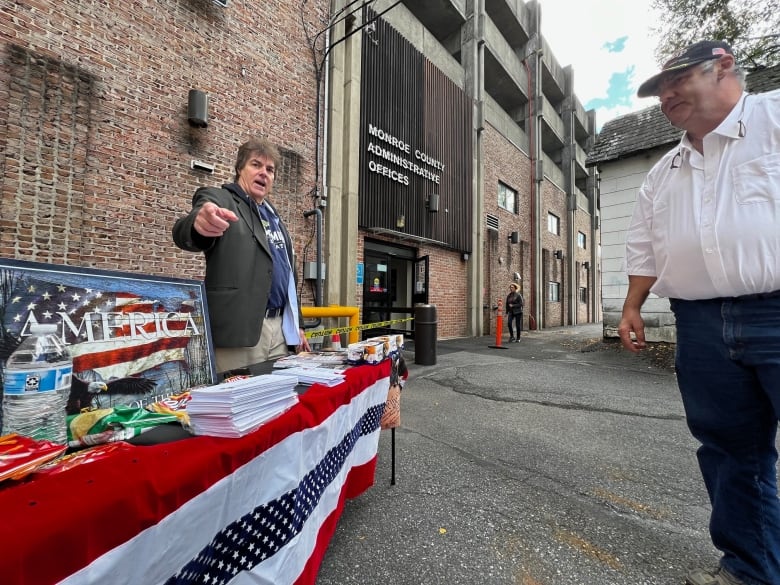 Man pointing from behind table decked out in red, white, blue