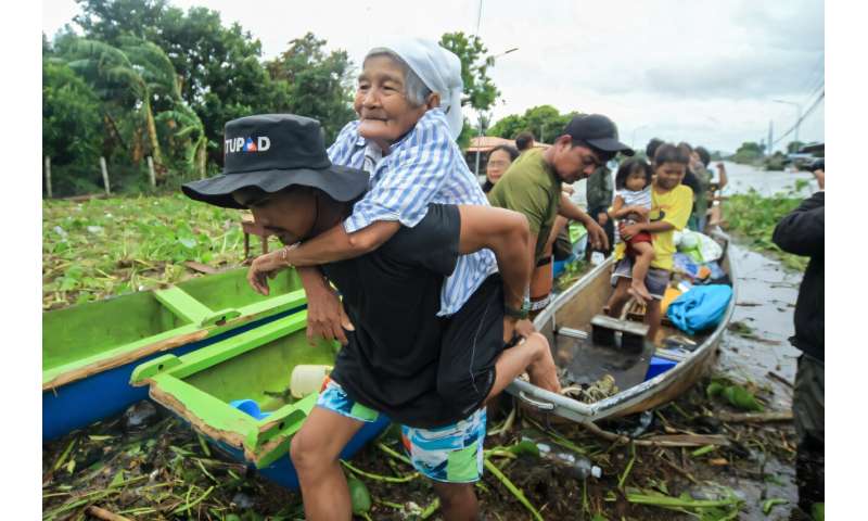 An elderly woman is carried by a volunteer rescuer as residents are evacuated to safer ground in Camarines Sur province