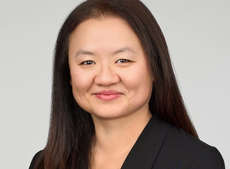 Portrait image of a smiling woman with long dark hair and wearing a black blazer.