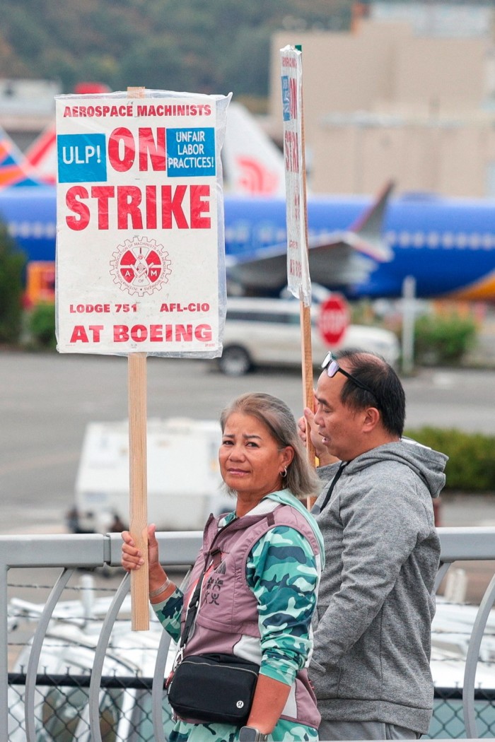 A man and a woman hold up signs promoting the Boeing strike