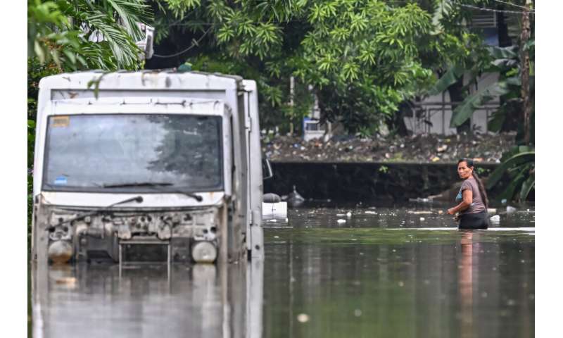 A woman wades through a street flooded by heavy rains from Tropical Storm Trami in Rizal province