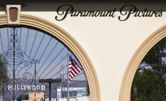 The Paramount Pictures logo is displayed in front of Paramount Studios with the Hollywood sign visible 