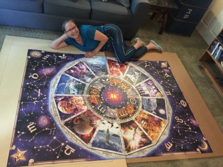 Photo of a woman in front of a very large puzzle.