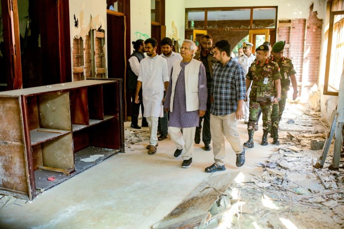 The interim leader with officials and military officers in a badly damaged room at the residence