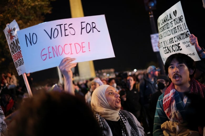 People with signs accusing Harris of abetting genocide