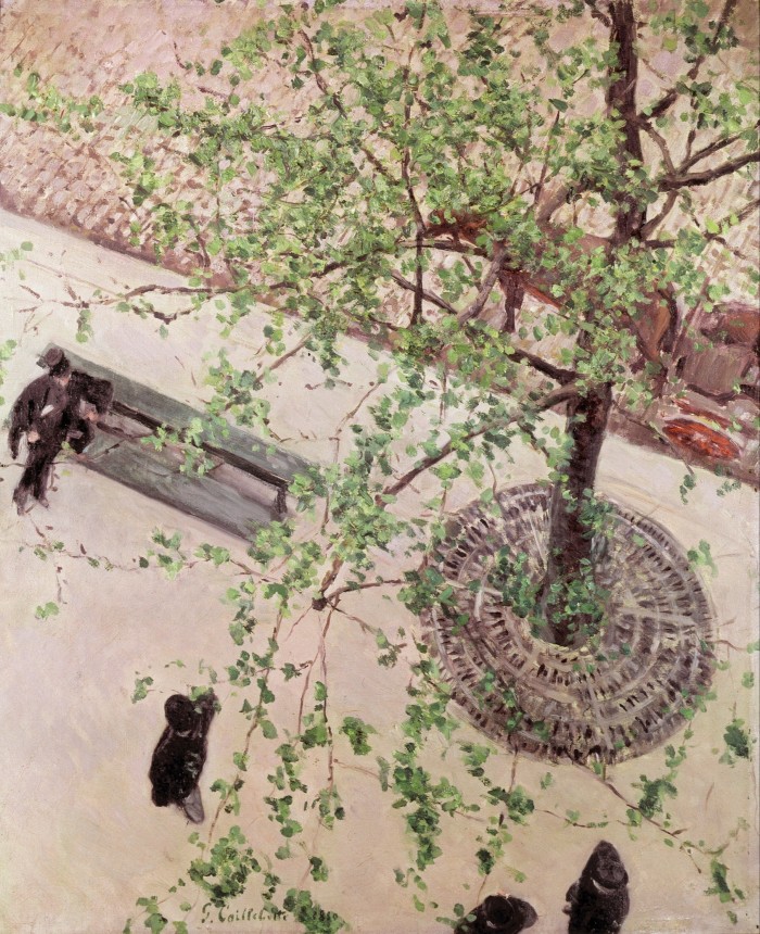 Aerial view of an urban street scene showing men in dark clothes walking or sitting on a bench next to a leafy tree