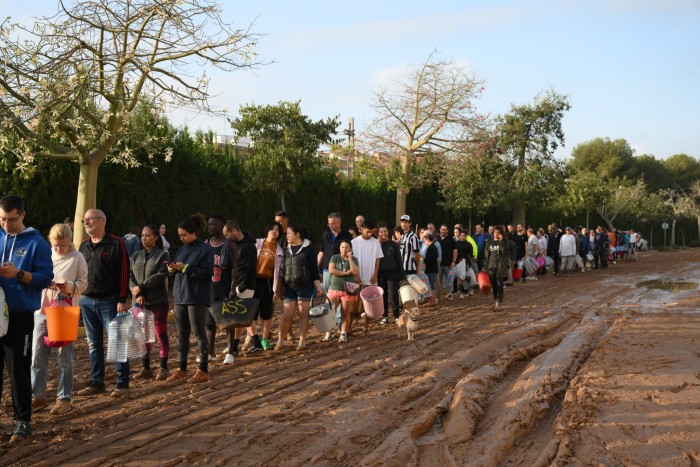 People line up to collect water from after flooding hit large parts of Valencia, Spain