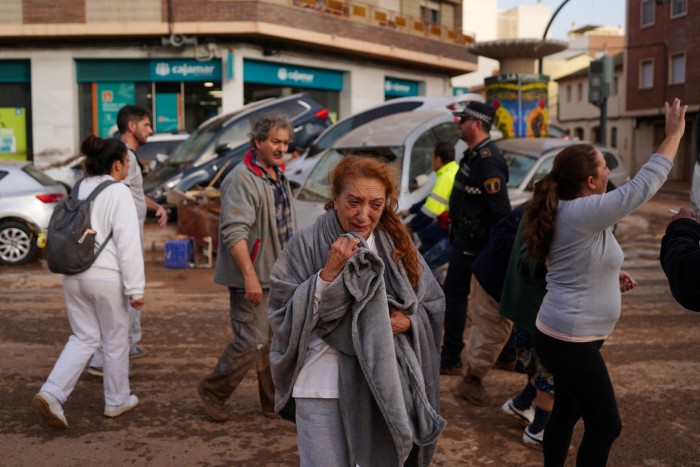 A woman reacts in a street covered in mud following deadly floods  in Valencia’s De La Torre neighbourhood, eastern Spain