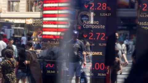 Reflections of pedestrians are seen on the glass displaying stock market information at the Nasdaq MarketSite in New York