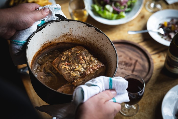 A man’s hands holding a casserole dish containing slow-cooked short rib at the Canton Arms