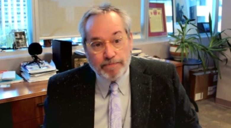 David Harrigan is wearing a jacket and tie sitting in an office.