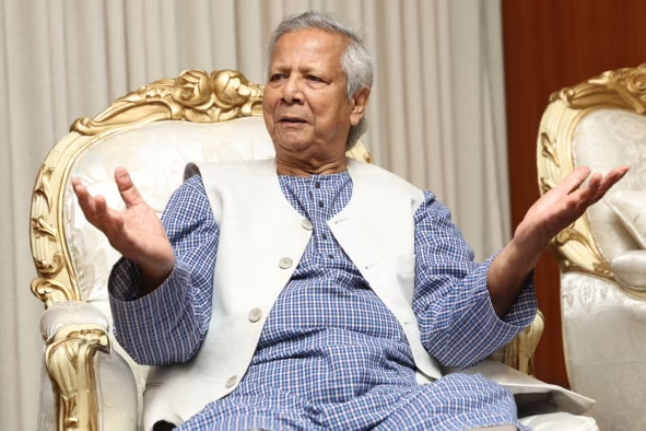 Muhammad Yunus sitting in a chair with both hands raised