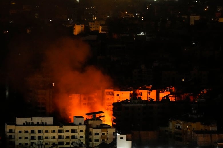 A nighttime photo shows what appears to be multistorey residential buildings, with orange fire between them.