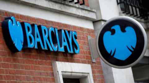 A Barclays Bank branch in London, featuring the bank's name in large blue letters on a brick wall and its logo, a blue eagle, on a circular sign