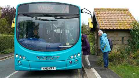 Passengers climb aboard a bus as it travels down the North Yorkshire coast between Saltburn By The Sea and Whitby