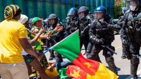 Police in Geneva hold back people protesting against Cameroon’s president Paul Biya