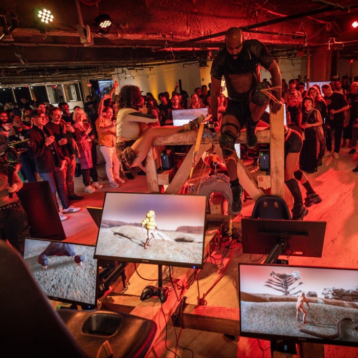 Gamers stand on a large wooden contraption with screens 