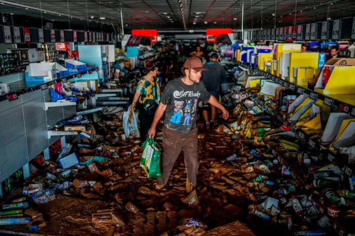 People pick up goods in a supermarket affected by the floods in Valencia