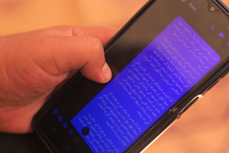 Man holds cellphone showing a text in Arabic.