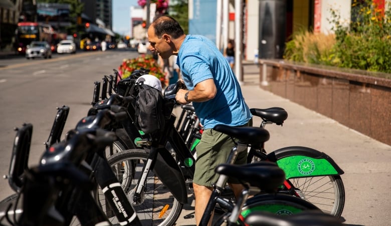 A man is seen putting a bike in a Bike Share rack in Toronto.