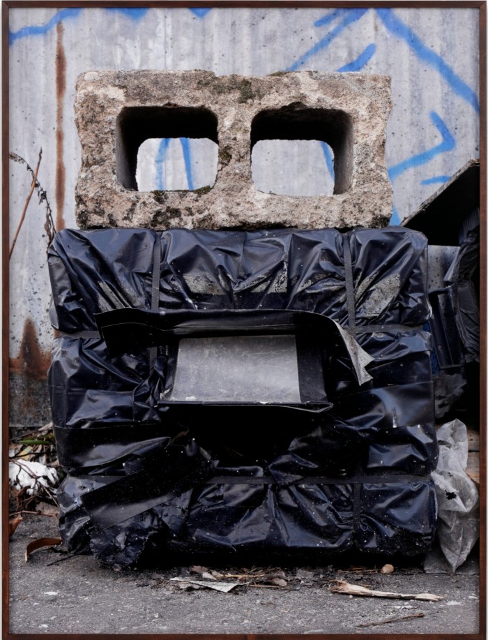 A huge concrete breezeblock , the lower half of which is covered by black bin bags