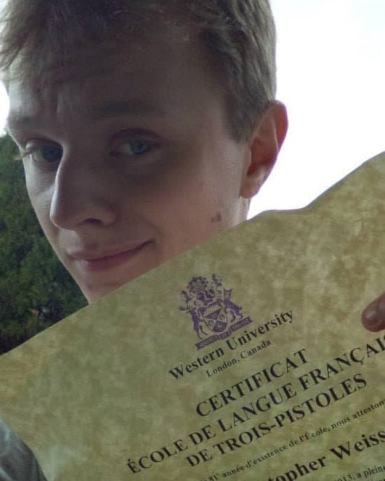 A man smiles at the camera while holding a certificate with his name on it 