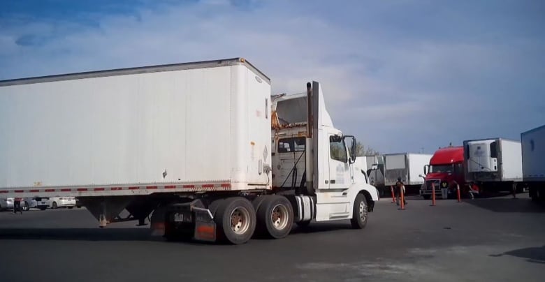 A long big-rig truck turning into a parking lot.