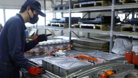 An employee checks modules of a used lithium-ion electric vehicle battery in a case at the 4R Energy factory in Namie, Fukushima Prefecture, Japan