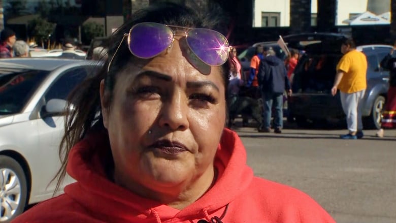 A woman wearing an orange hoodie looks at the camera. 