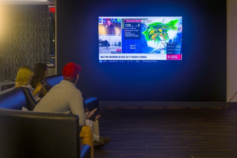 People pay attention to a TV report on the developing Hurricane Milton at a restaurant in Orlando, Fla., on Wednesday.