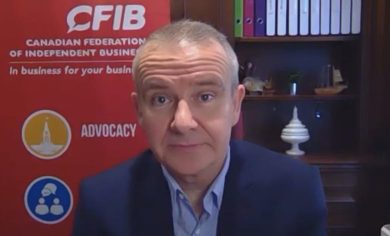 A man in a collared shirt and jacket sits in front of a poster that reads "Canadian Federation of Independent Business."