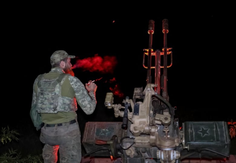 A Ukrainian soldier smokes a cigarette while watching for incoming Russian kamikaze drones, in Ukraine's Kherson region.