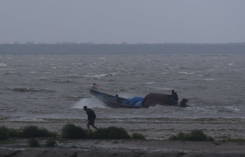 Fishermen work to bring their boat back to shore during high tide in India's Odisha state, ahead of the arrival of a tropical storm.