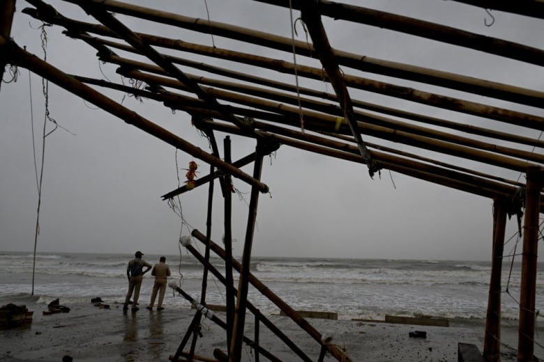 Police are seen near the site of a damaged shop at a beach in Balasore, India, ahead of the arrival of a tropical storm.